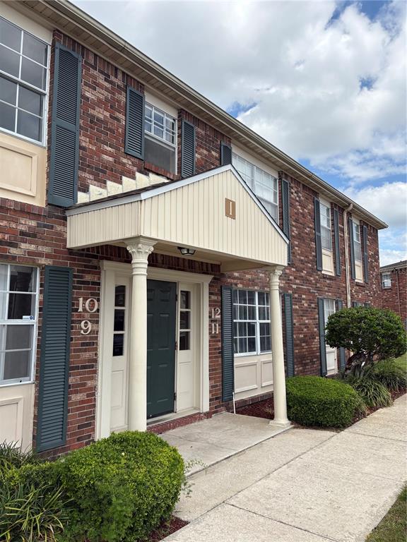 A brick apartment building exterior features a covered entrance with white columns and numbered doors — 1920 E EDGEWOOD DRIVE UNIT I 10, LAKELAND, FL