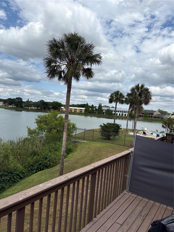 A wooden deck overlooks a lake with palm trees and a distant apartment complex — 1920 E EDGEWOOD DRIVE UNIT I 10, LAKELAND, FL