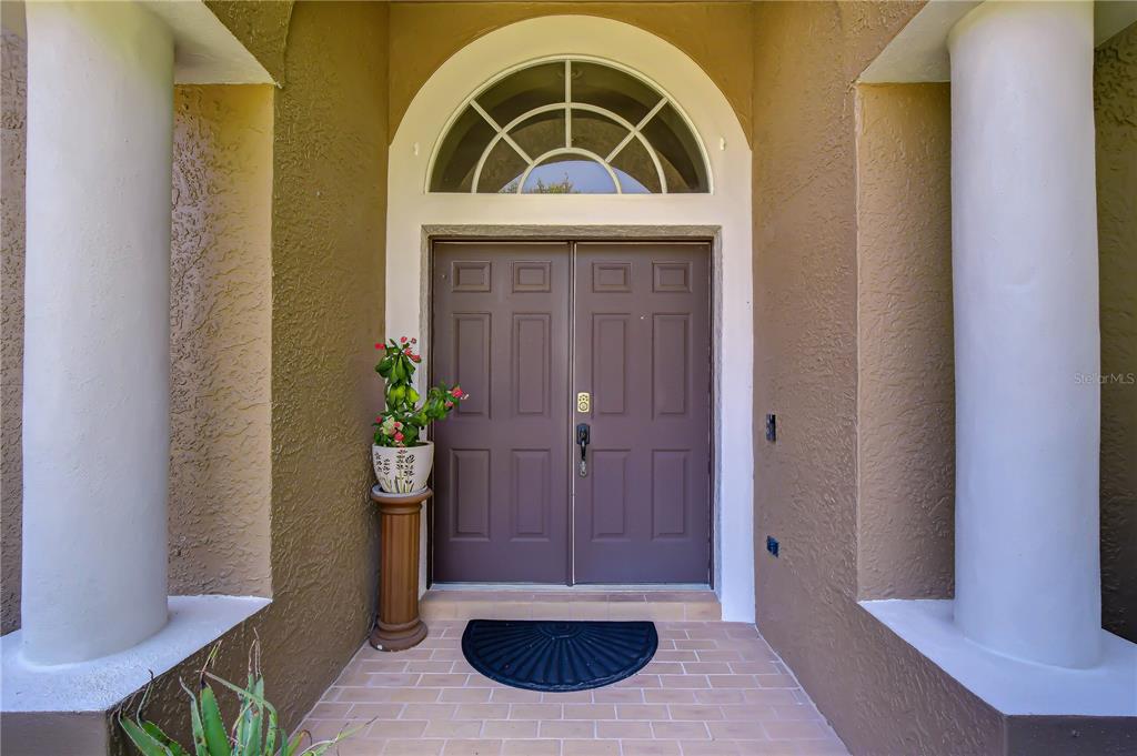 A front entryway features double doors, a semi-circular transom window, and two large white columns — 9244 BRINDLEWOOD DRIVE, ODESSA, FL