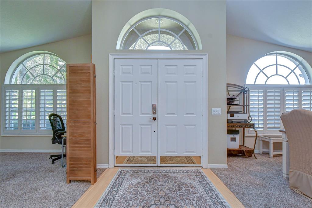 A foyer features a double front door, arched windows, carpeted flooring, and a decorative rug — 9244 BRINDLEWOOD DRIVE, ODESSA, FL