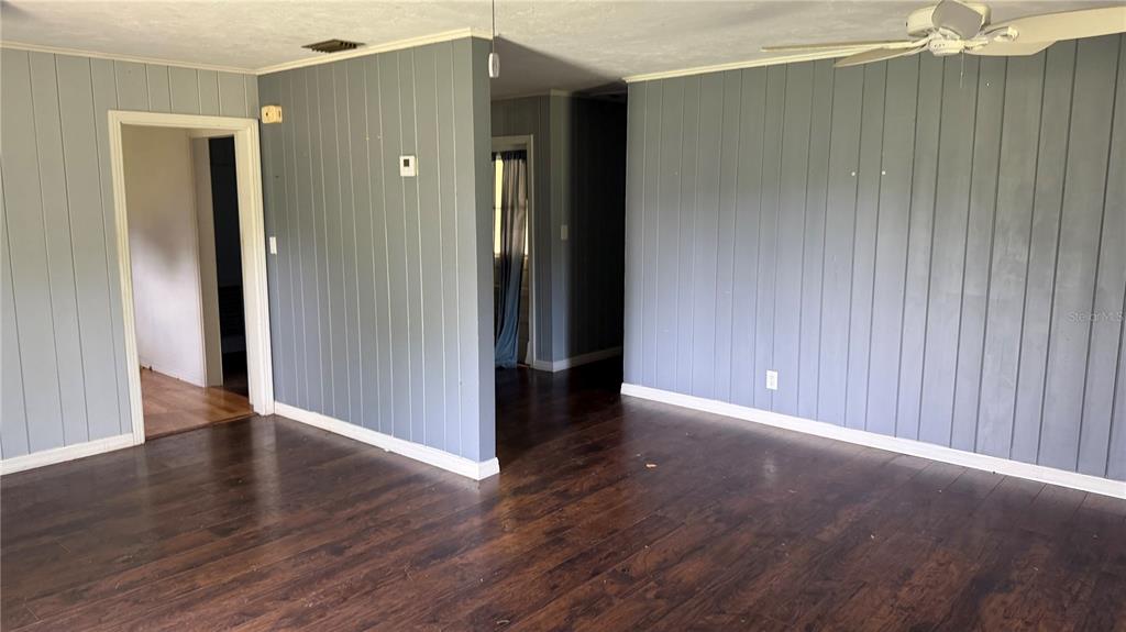 A living room features dark wood-look flooring and gray vertical paneled walls — 4611 FRUITVILLE ROAD, SARASOTA, FL