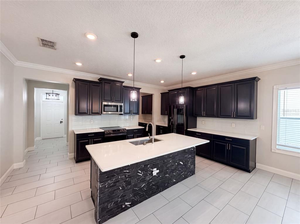 A kitchen features dark cabinets, white countertops, and a black stone-tiled kitchen island — 1423 PRO SHOP COURT, DAVENPORT, FL