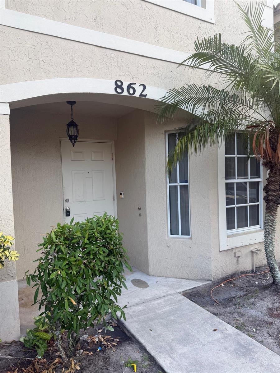 The exterior of a tan residential building features a covered entryway with the number 862 — 862 Summit Lake Drive, West Palm Beach FL 33406, WEST PALM BEACH, FL