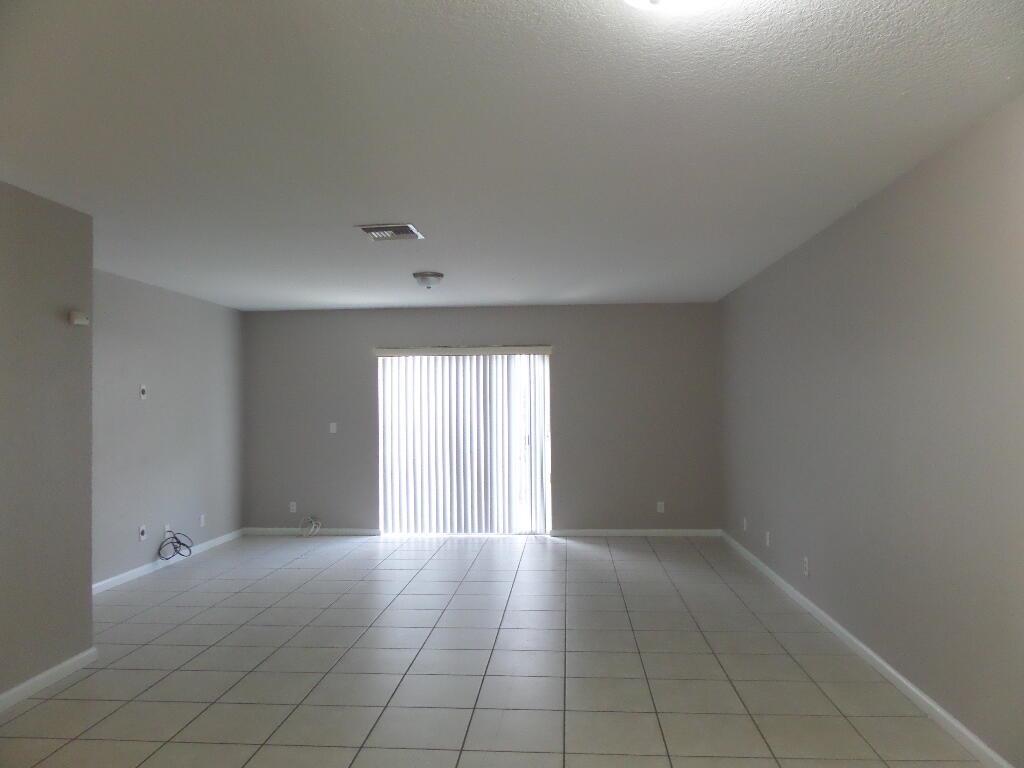 An empty room with light-colored tile flooring, gray walls, and a sliding glass door — 862 Summit Lake Drive, West Palm Beach FL 33406, WEST PALM BEACH, FL