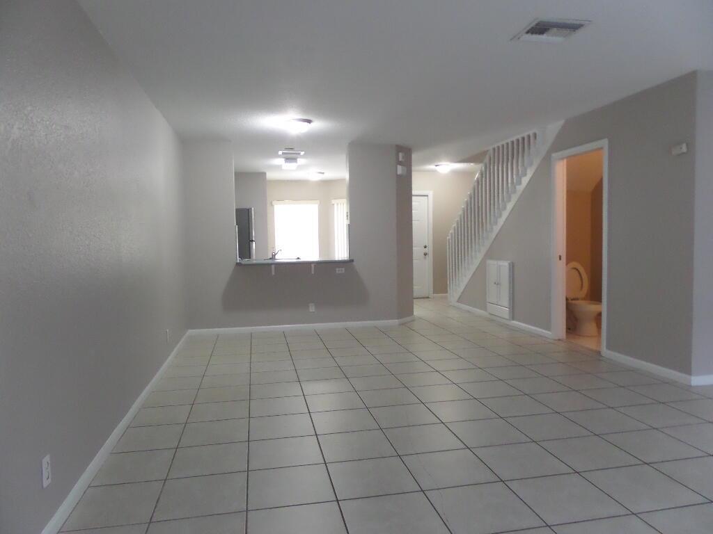 An open-concept living area features light tile flooring, a kitchen pass-through, and a staircase — 862 Summit Lake Drive, West Palm Beach FL 33406, WEST PALM BEACH, FL