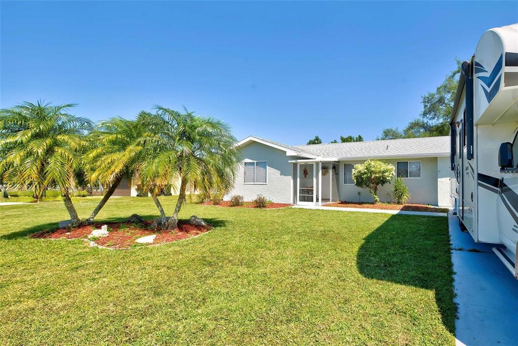 A light-colored house with a front lawn, palm trees, and a parked RV — 6792 HIGDON ROAD, NORTH PORT, FL