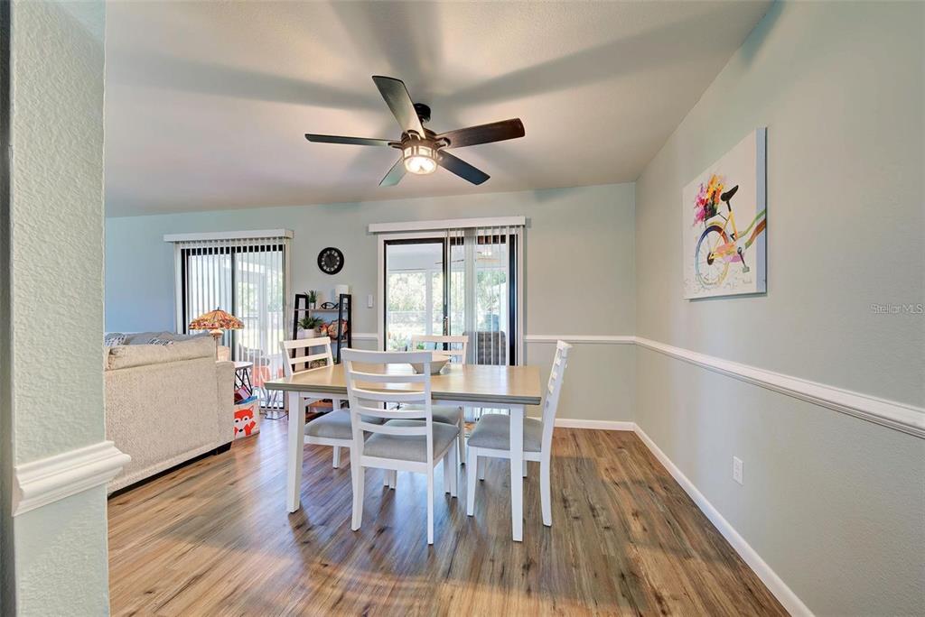 A dining area features a wooden table, white chairs, wood-look flooring, and a ceiling fan — 6792 HIGDON ROAD, NORTH PORT, FL