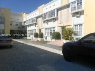 A multi-story apartment building exterior features light-colored walls, multiple windows, and a gravel parking area — 1612 Drexel Avenue # 8, Miami Beach FL 33139, MIAMI BEACH, FL