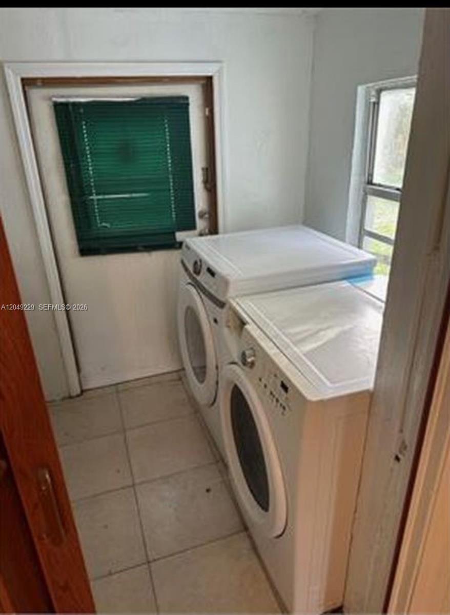 A laundry room features a white washer and dryer set, tiled flooring, and a door — 2736 NW 2nd St # 2736, Pompano Beach FL 33069, POMPANO BEACH, FL