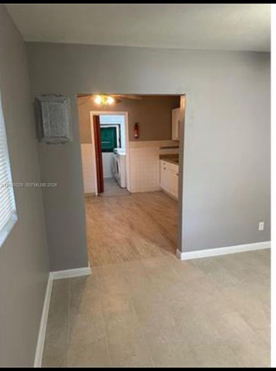 A view from a tiled room looking through a doorway into a kitchen with wood-look flooring — 2736 NW 2nd St # 2736, Pompano Beach FL 33069, POMPANO BEACH, FL