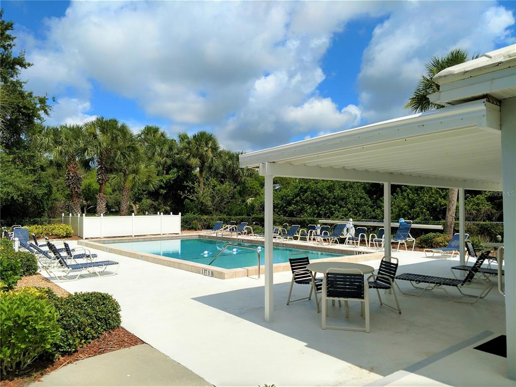 A swimming pool with lounge chairs sits on a patio under a covered lanai — 208 CERROMAR WAY S UNIT 26, VENICE, FL