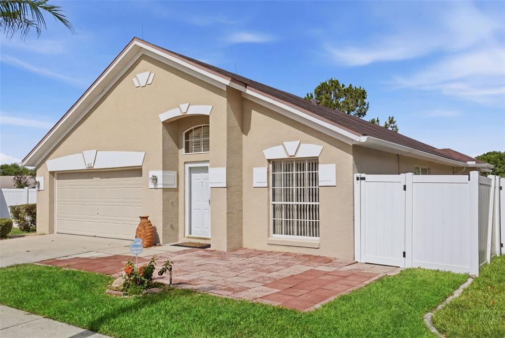 A single-story house with a beige stucco exterior, a garage, and a front patio — 632 CYPRESS TREE COURT, ORLANDO, FL