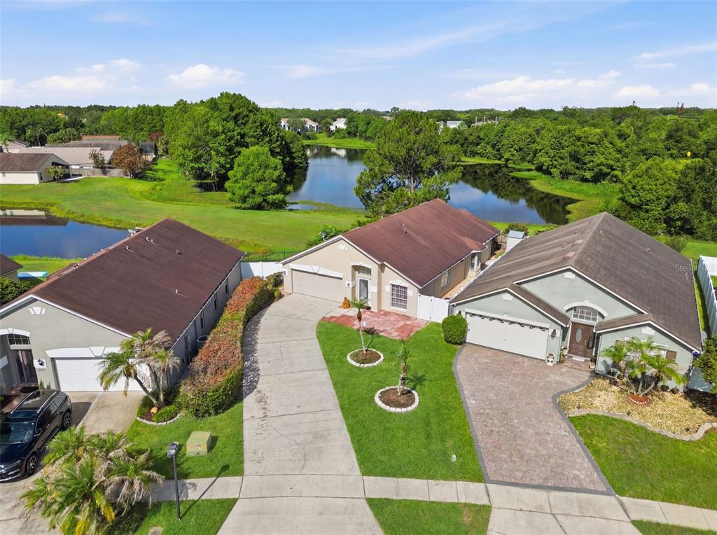 An aerial view shows three suburban houses with driveways and lawns near a small lake — 632 CYPRESS TREE COURT, ORLANDO, FL