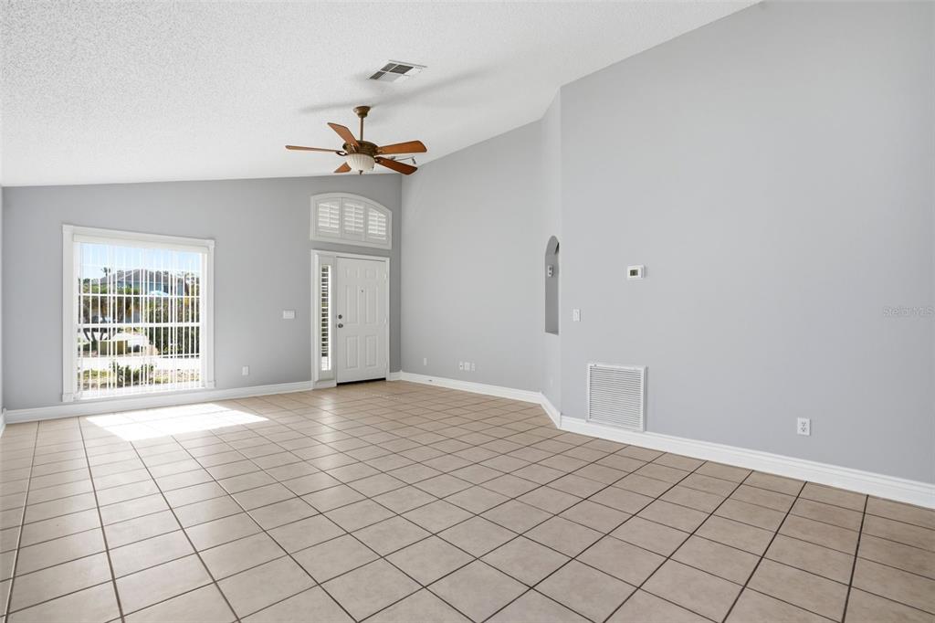 An empty living room features light gray walls, a vaulted ceiling, and beige tiled flooring — 632 CYPRESS TREE COURT, ORLANDO, FL