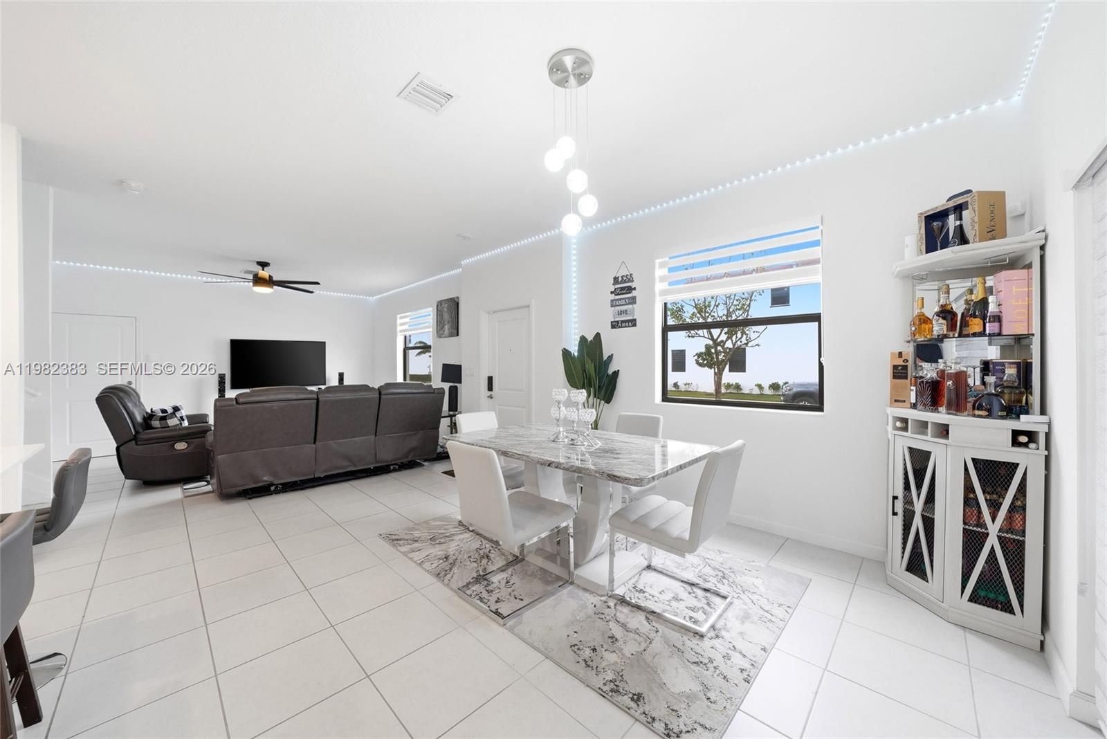 A dining area with a marble table and white chairs sits adjacent to a living room — 13091 SW 232nd Ln, Miami FL 33170, MIAMI, FL