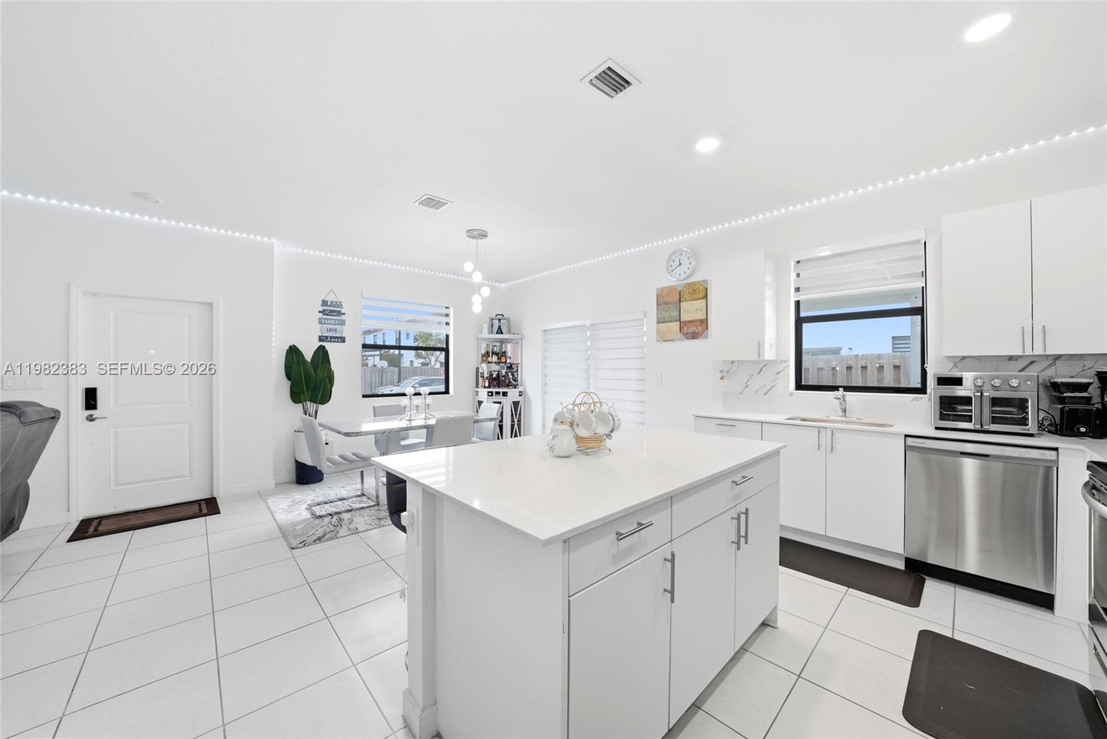 A white kitchen features a central island, stainless steel appliances, and an adjacent dining area — 13091 SW 232nd Ln, Miami FL 33170, MIAMI, FL