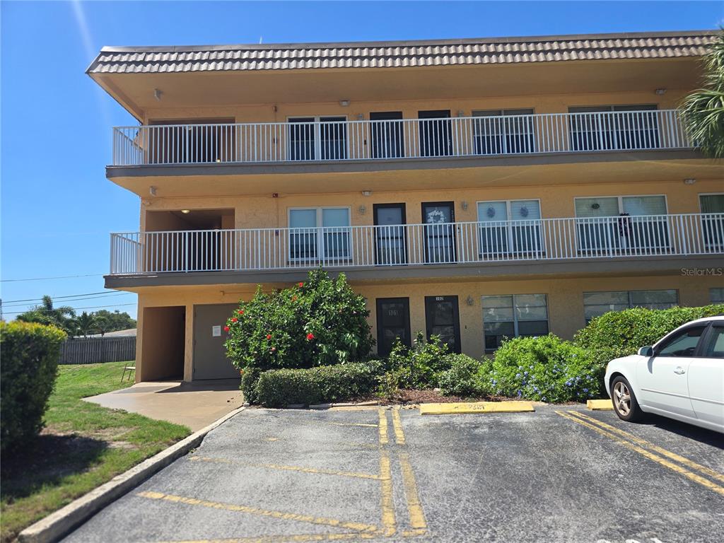 A three-story apartment building with balconies and a parking lot in the foreground — 6400 46TH AVENUE N UNIT 301, KENNETH CITY, FL