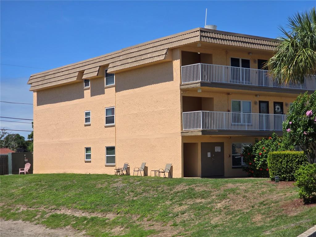 A three-story tan apartment building features white railings on the balconies and small windows — 6400 46TH AVENUE N UNIT 301, KENNETH CITY, FL