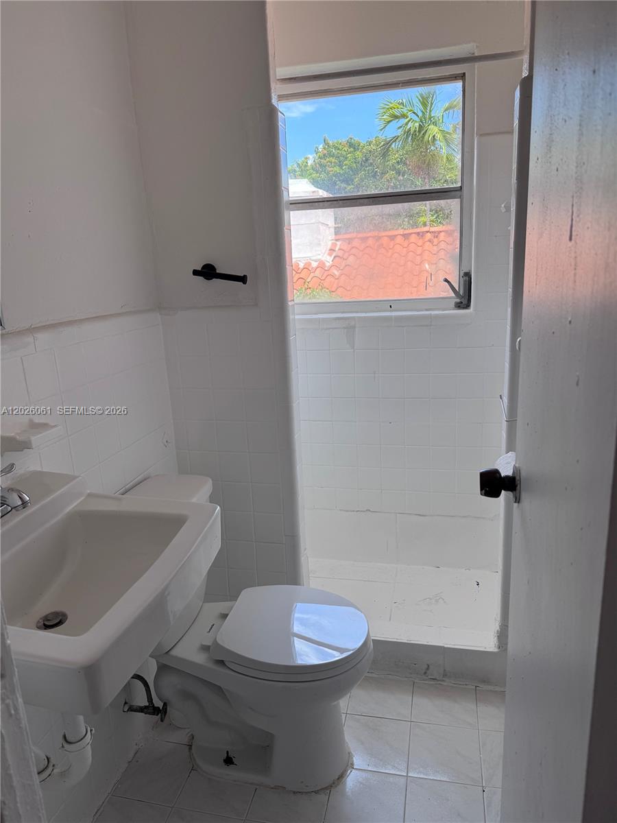 A small bathroom features a white pedestal sink, a toilet, and a tiled shower stall — 825 Alton Road # 8, Miami Beach FL 33139, MIAMI BEACH, FL