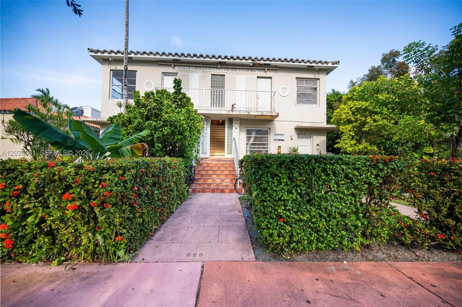 A two-story apartment building with a tiled roof, a central balcony, and a landscaped walkway — 825 Alton Road # 8, Miami Beach FL 33139, MIAMI BEACH, FL