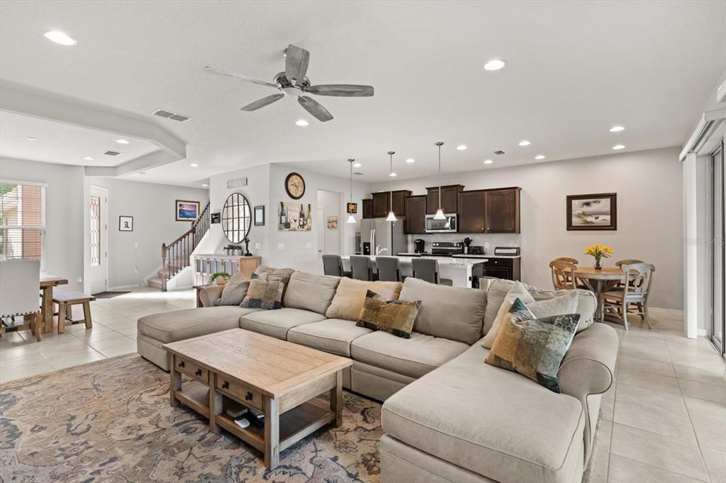 A spacious open-concept living room features a large sectional sofa, kitchen island, and dining area — 1483 EL CONTE DRIVE, DAVENPORT, FL