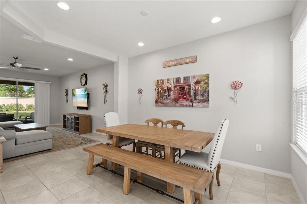 A dining area with a wooden table and bench sits adjacent to a living room — 1483 EL CONTE DRIVE, DAVENPORT, FL