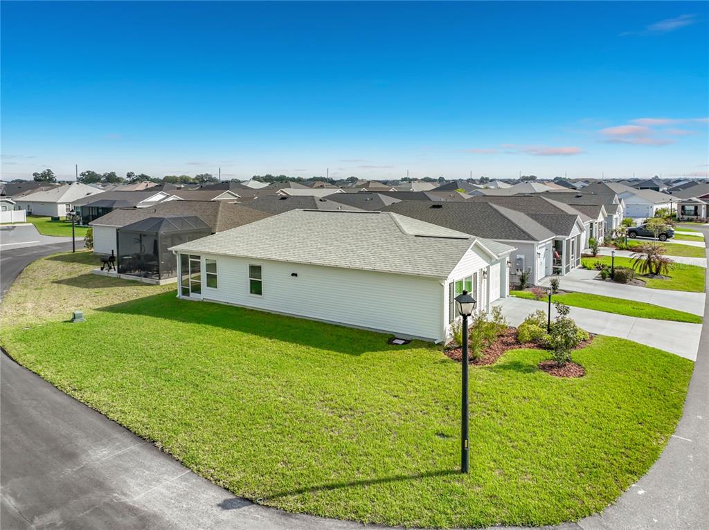 A white single-story house with a screened-in patio sits on a corner lot — 1763 BRODY COURT, THE VILLAGES, FL