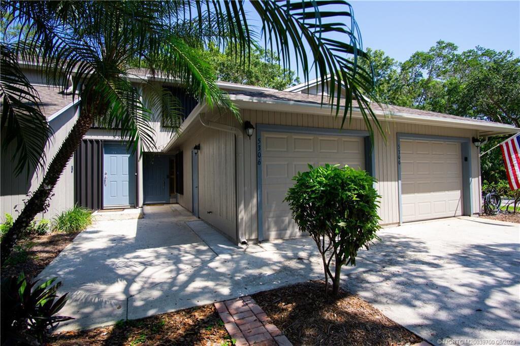 A two-story house exterior features light-colored siding, two garage doors, and a paved walkway — 5300 SE Schooner Oaks Way, Stuart FL 34997, STUART, FL