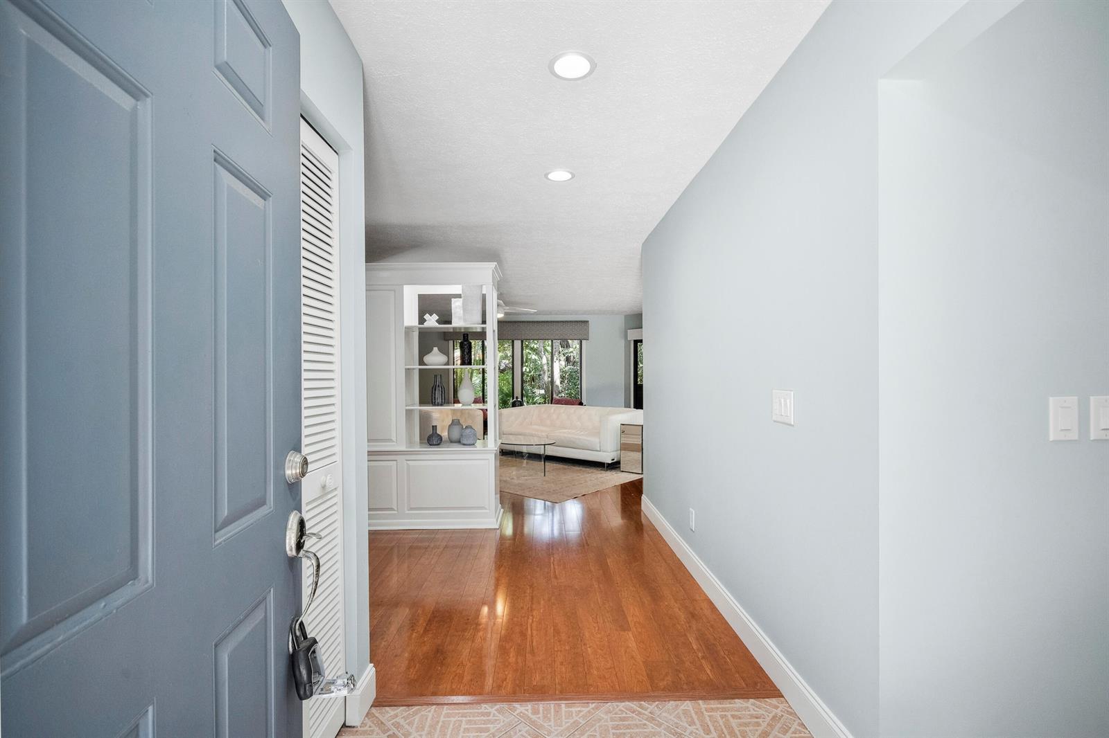 An entryway with a blue door opens into a living area with hardwood floors — 5300 SE Schooner Oaks Way, Stuart FL 34997, STUART, FL