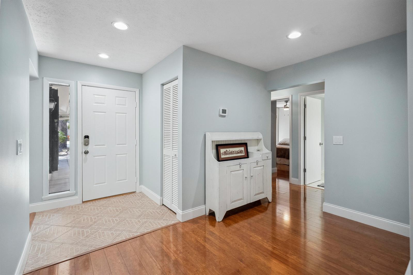 An entryway features light blue walls, hardwood floors, a white front door, and a cabinet — 5300 SE Schooner Oaks Way, Stuart FL 34997, STUART, FL