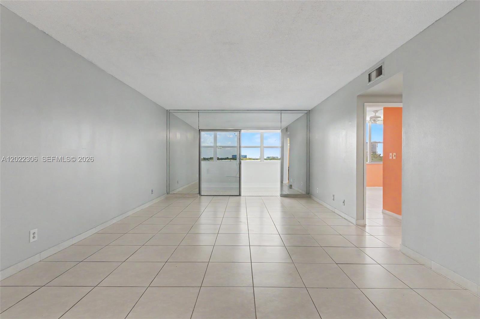 An empty room with light-colored tile flooring, mirrored walls, and a sliding glass door — 4330 Hillcrest Dr # 506, Hollywood FL 33021, HOLLYWOOD, FL