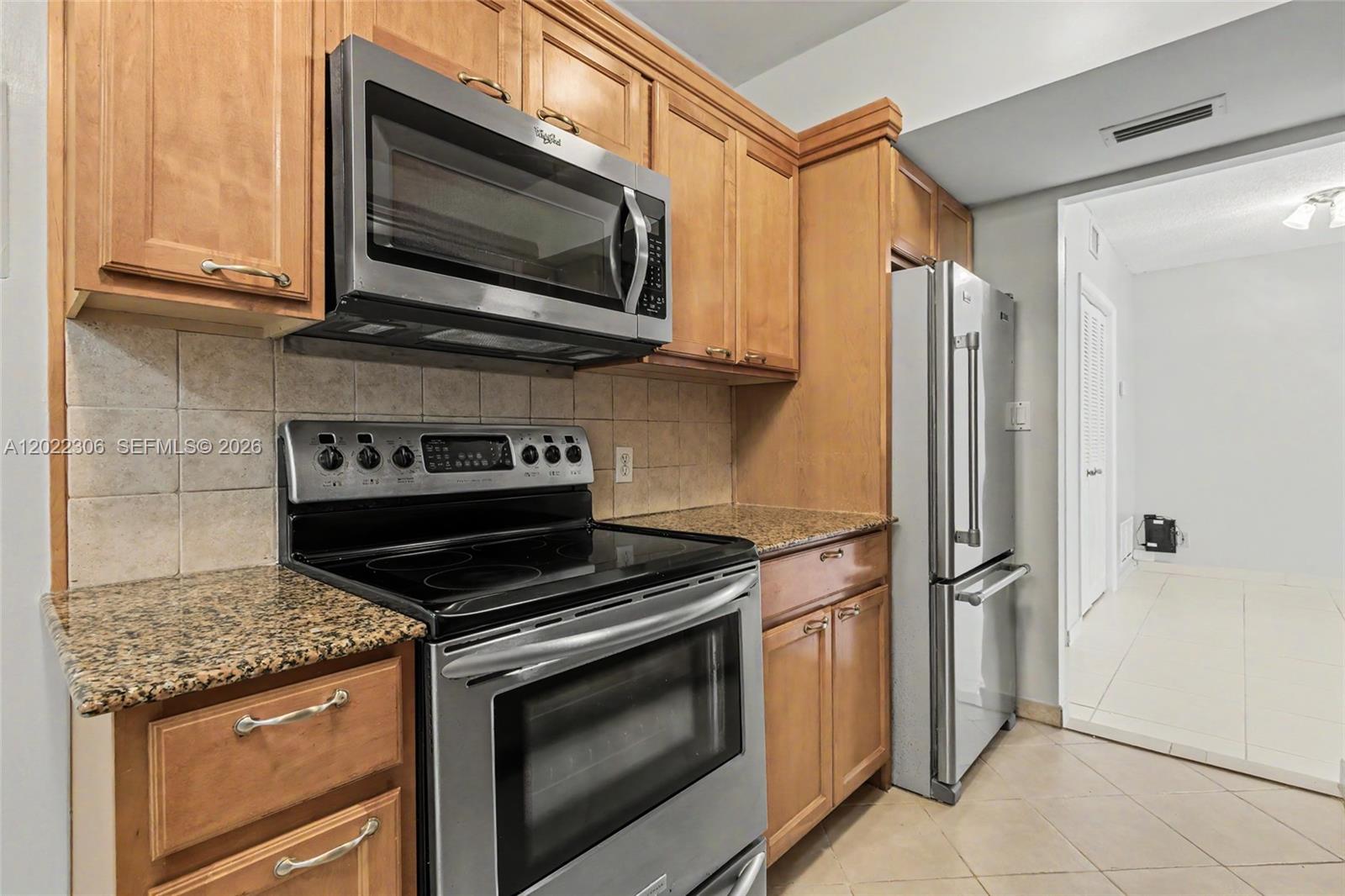A kitchen features wooden cabinets, granite countertops, and stainless steel appliances — 4330 Hillcrest Dr # 506, Hollywood FL 33021, HOLLYWOOD, FL