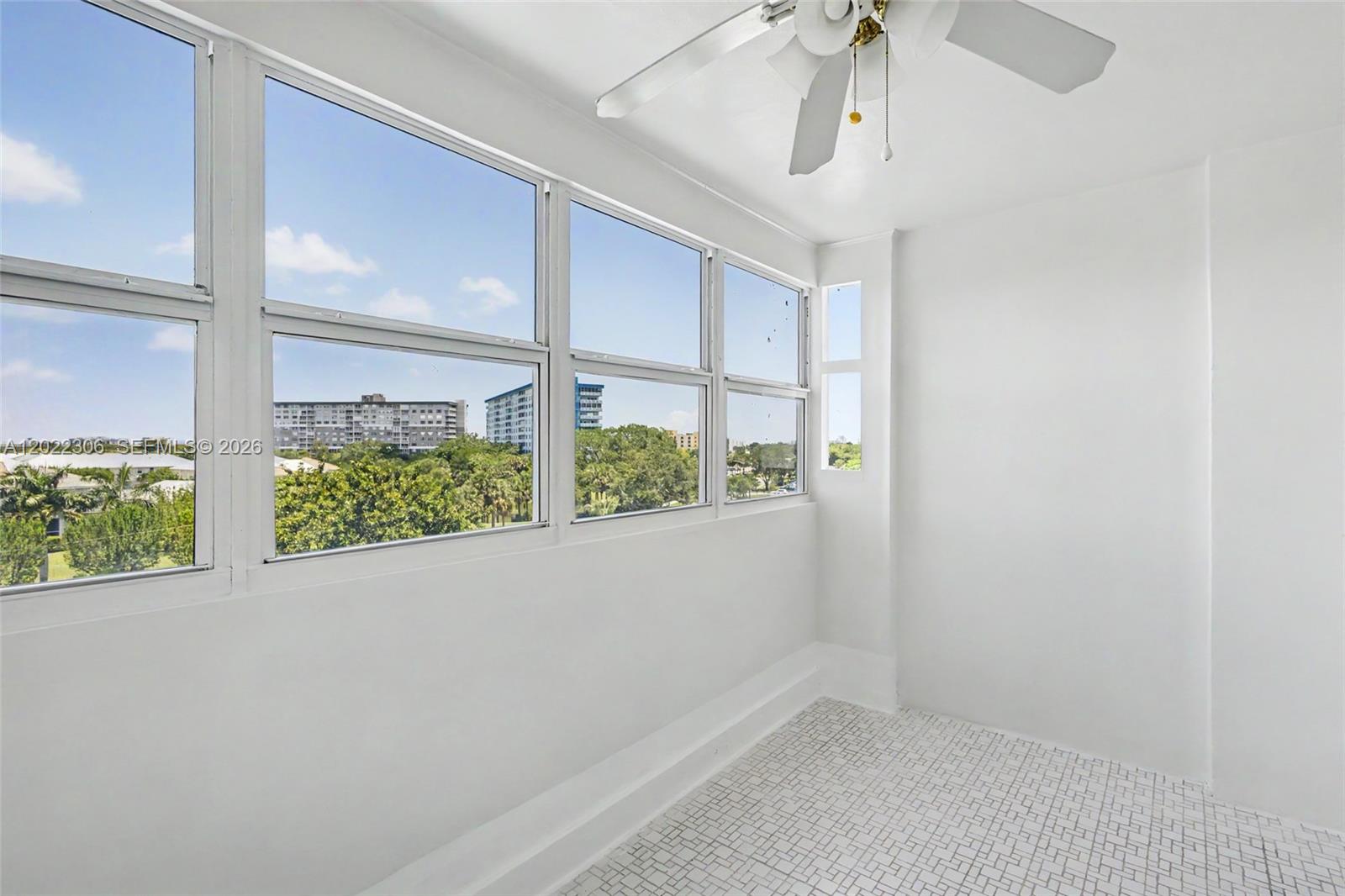 A sunroom with white walls, tiled flooring, a ceiling fan, and large windows overlooking trees — 4330 Hillcrest Dr # 506, Hollywood FL 33021, HOLLYWOOD, FL
