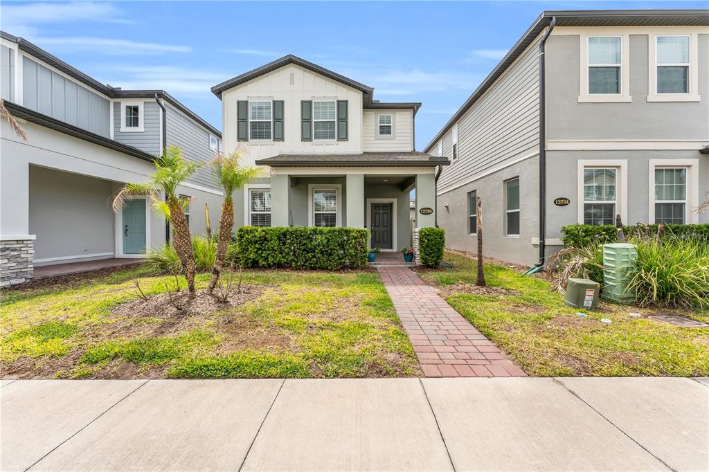 A two-story house with a brick walkway, green landscaping, and a covered front porch — 12790 BRODLOVE LANE, WINTER GARDEN, FL