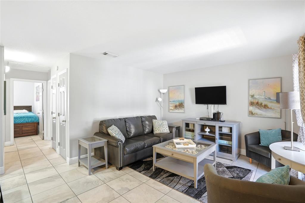 A living room features a dark leather sofa, a coffee table, and a wall-mounted television — 8911 BLIND PASS ROAD UNIT 302, ST PETE BEACH, FL