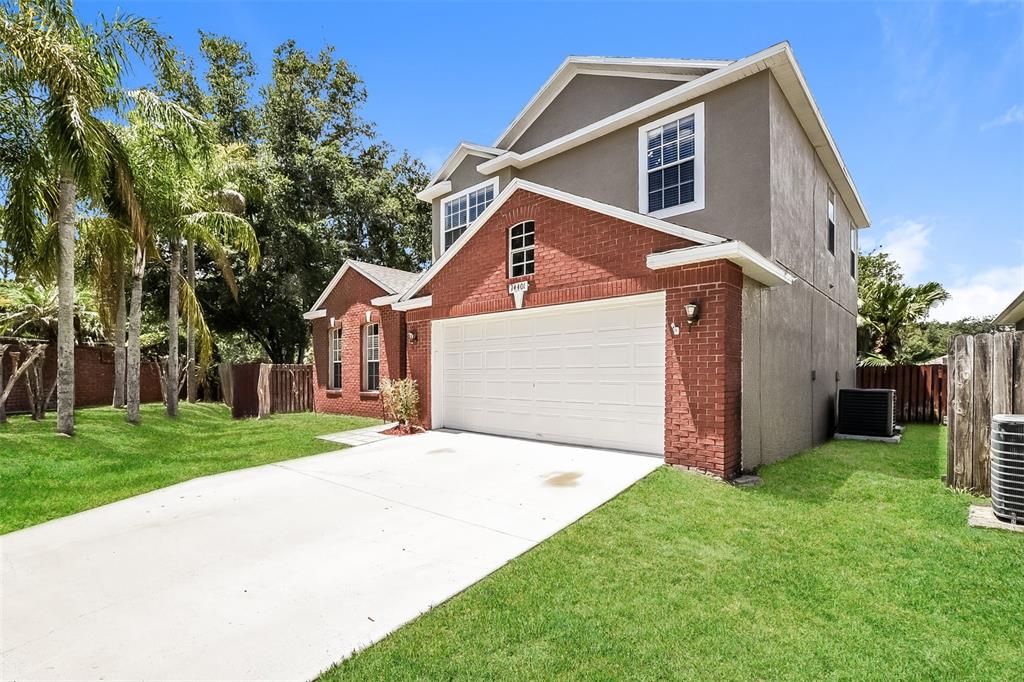 A two-story house with a brick facade, white garage door, and a grassy front yard — 14401 KRISTENRIGHT LANE, ORLANDO, FL