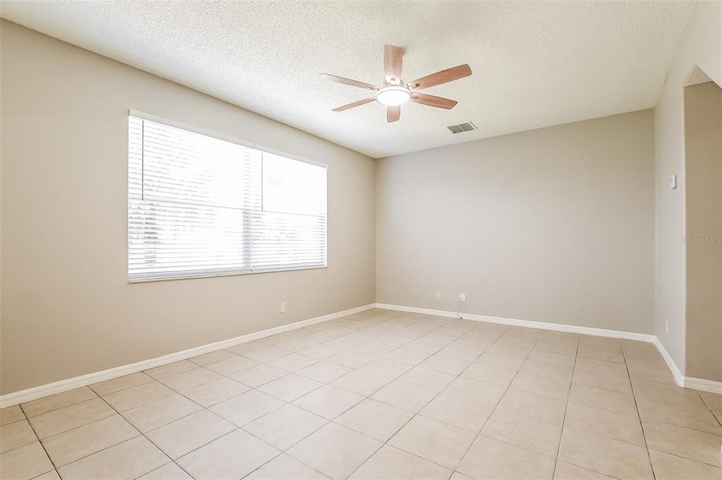 An empty room features beige tile flooring, light-colored walls, and a ceiling fan — 14401 KRISTENRIGHT LANE, ORLANDO, FL