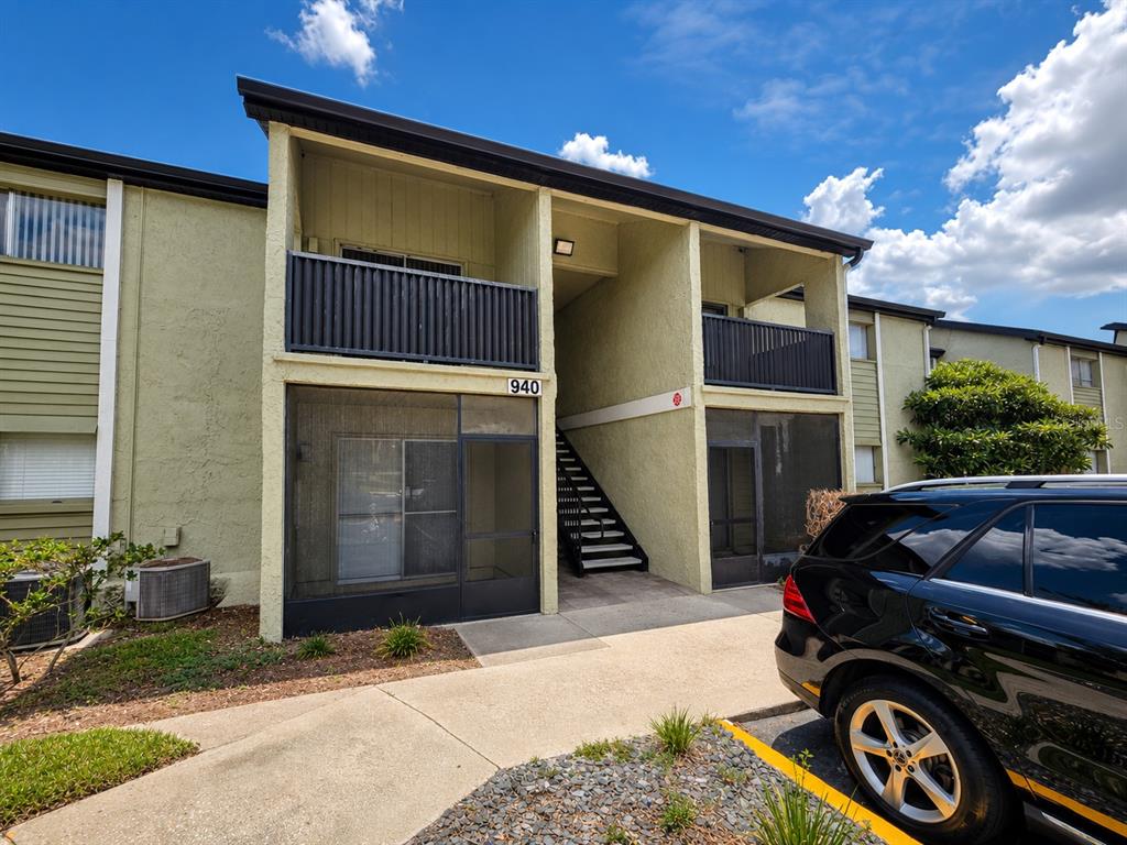 A two-story apartment building exterior features a screened-in ground floor, upper balcony, and exterior stairs — 940 LAKE DESTINY ROAD UNIT G, ALTAMONTE SPRINGS, FL