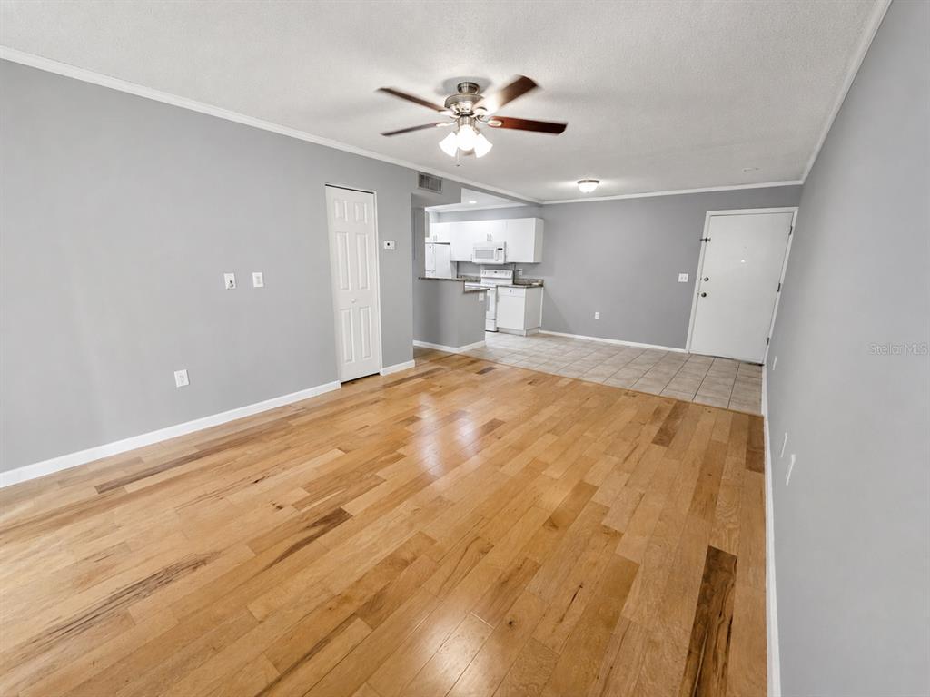 An open-concept living room with hardwood floors leads to a tiled kitchen area — 940 LAKE DESTINY ROAD UNIT G, ALTAMONTE SPRINGS, FL