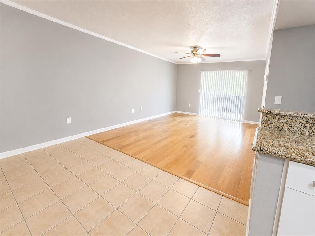 An open-concept living area features light wood flooring, gray walls, and a tiled kitchen floor — 940 LAKE DESTINY ROAD UNIT G, ALTAMONTE SPRINGS, FL
