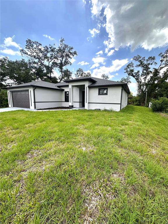 A modern, single-story house with a light-colored stucco exterior and a dark-trimmed garage — 4653 SAN LUIS TERRACE, NORTH PORT, FL
