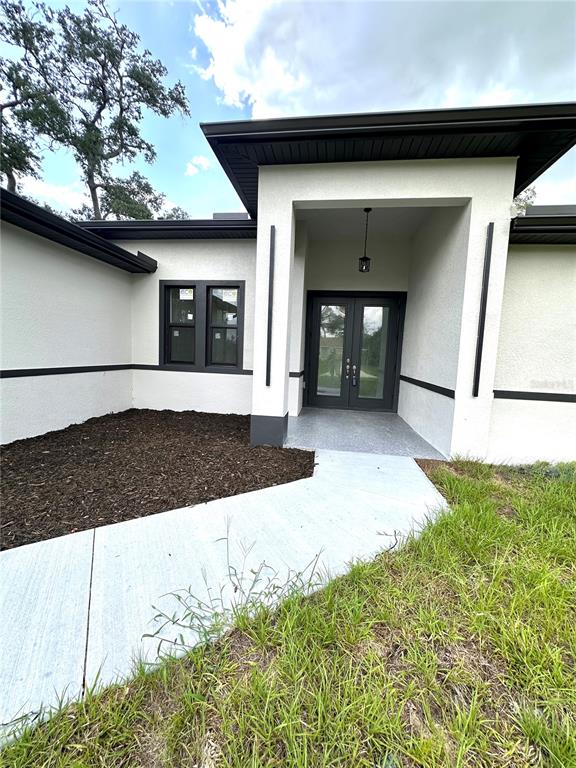 The exterior of a modern house features a covered entryway with double glass doors — 4653 SAN LUIS TERRACE, NORTH PORT, FL