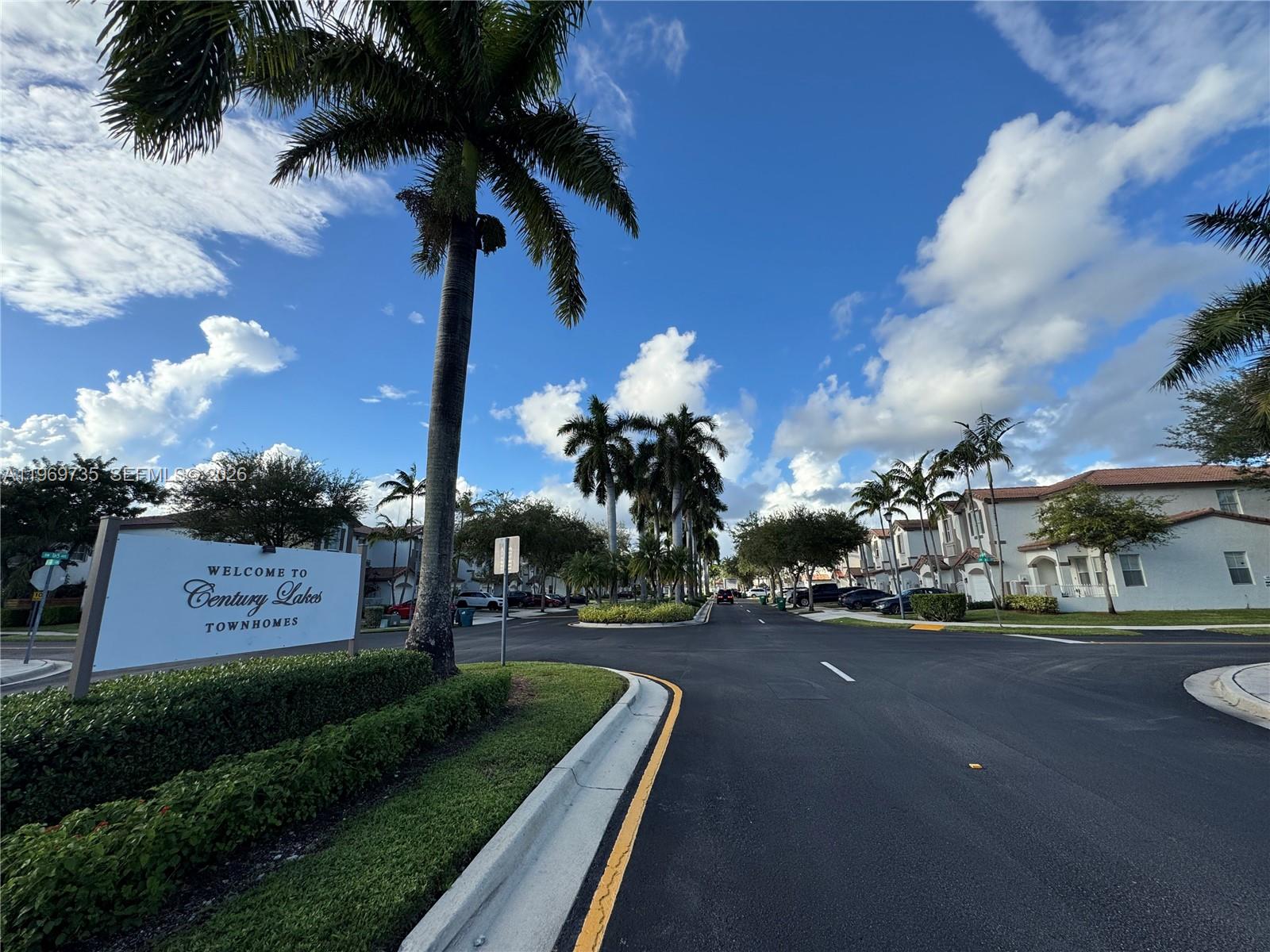 A sign for Century Lakes Townhomes stands beside a palm tree-lined street with residential buildings — 6243 SW 165th Ave, Miami FL 33193, MIAMI, FL