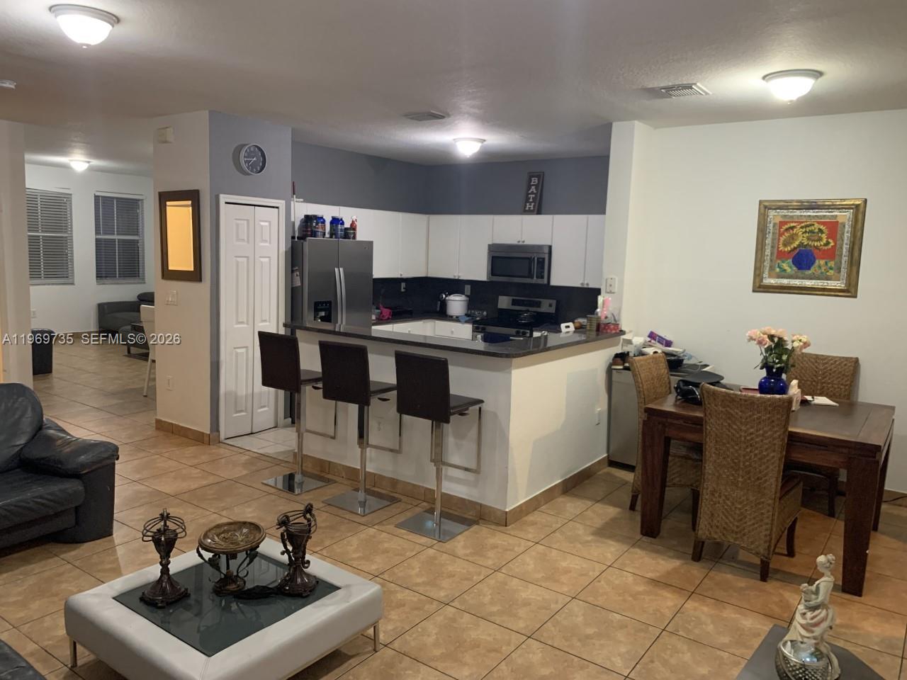 An open-concept kitchen with a breakfast bar, dining area, and living room with tile flooring — 6243 SW 165th Ave, Miami FL 33193, MIAMI, FL
