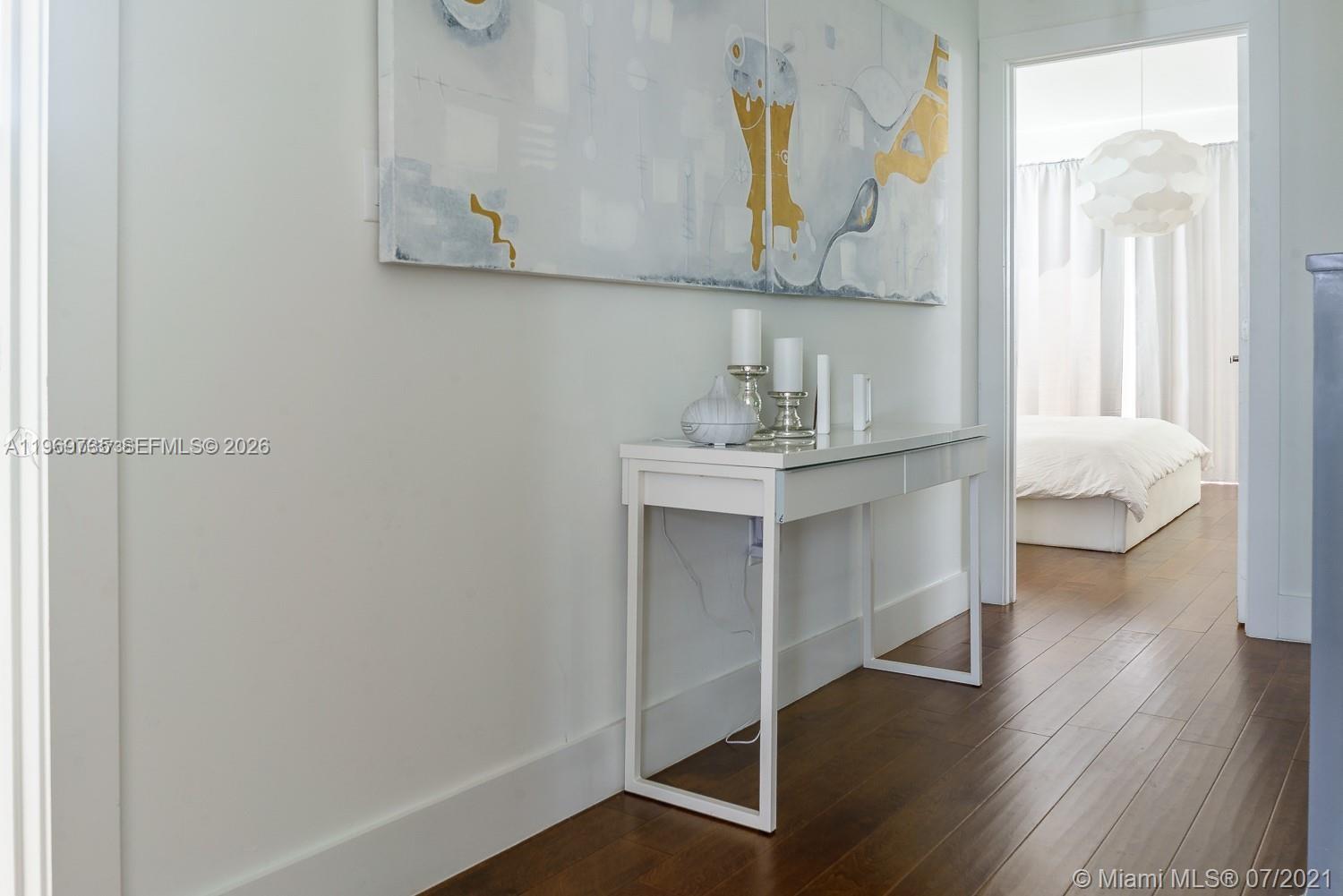 A white console table sits in a hallway with hardwood floors and abstract wall art — 6243 SW 165th Ave, Miami FL 33193, MIAMI, FL