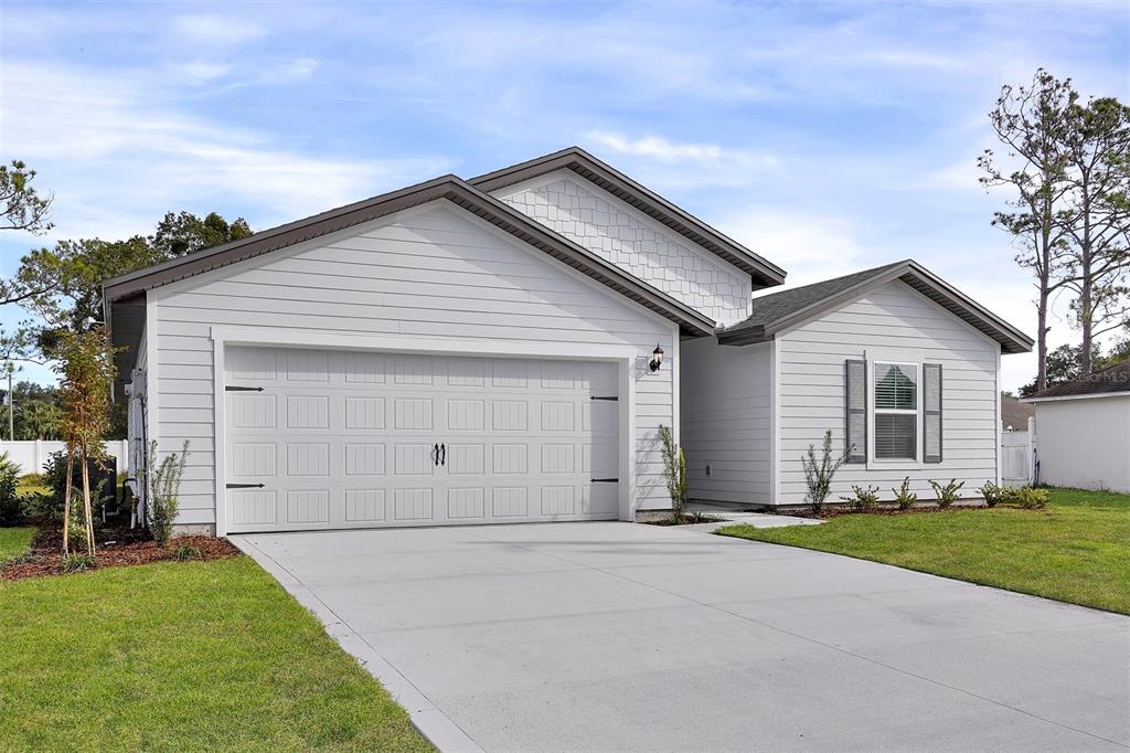 A single-story house with white horizontal siding, a two-car garage, and a shingled roof — 34 PRESIDENTIAL LANE, PALM COAST, FL