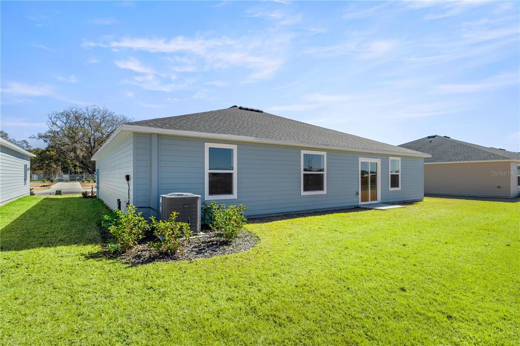 The exterior rear view of a light blue single-story house with a grassy yard — 8367 SW 41ST TERRACE, OCALA, FL