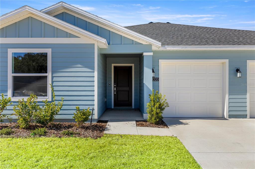 A blue house exterior features a dark front door, a garage, and a small lawn — 8367 SW 41ST TERRACE, OCALA, FL