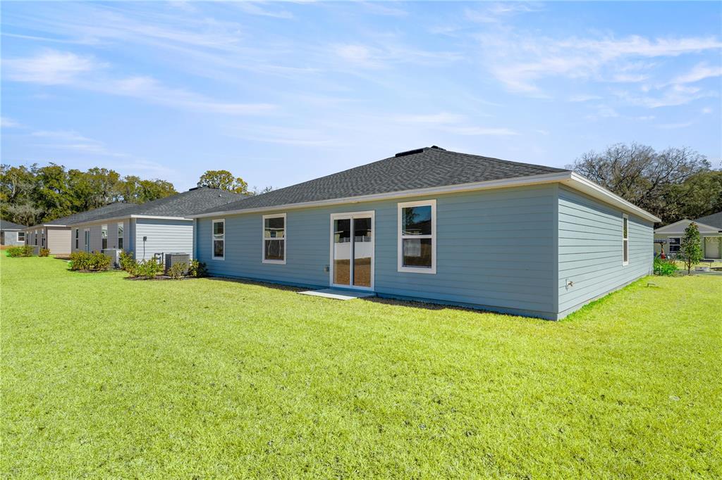 The exterior of a light blue, single-story house with a lawn and sliding glass doors — 8367 SW 41ST TERRACE, OCALA, FL