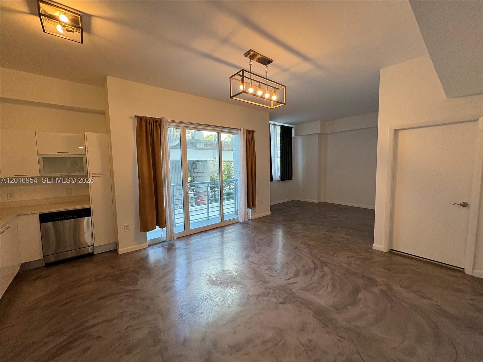 An open-concept living area features a kitchen, polished concrete floors, and a sliding glass door — 133 NE 2nd Ave # 210, Miami FL 33132, MIAMI, FL